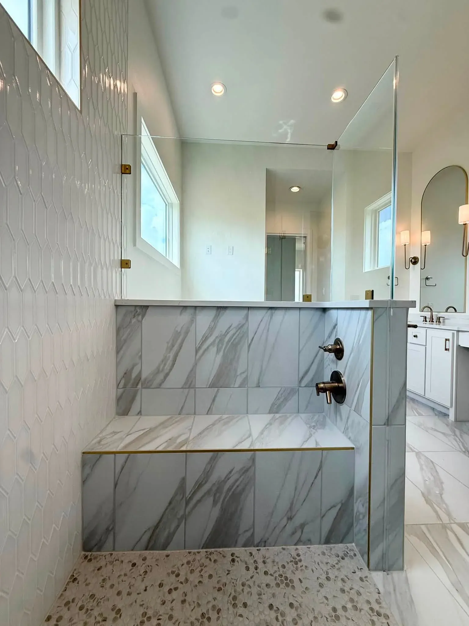 Finished marble-look walk-in shower with a custom bench and frameless glass