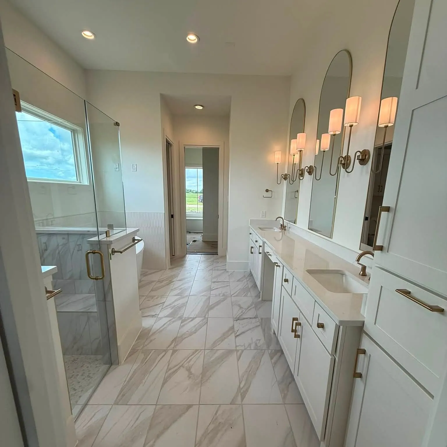 Finished primary bathroom with marble-look tile and a double vanity
