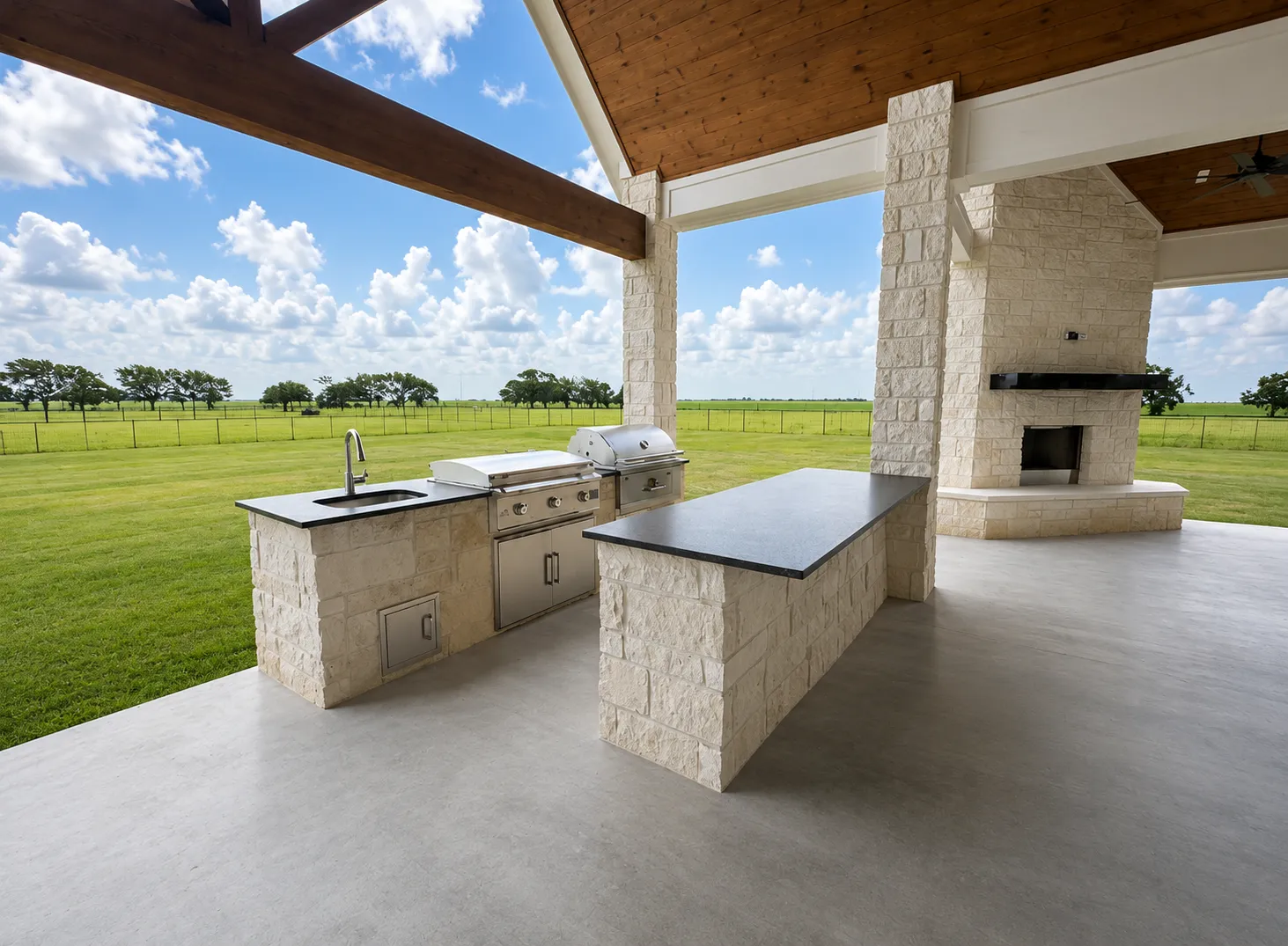 Covered outdoor kitchen with natural stone masonry and fireplace